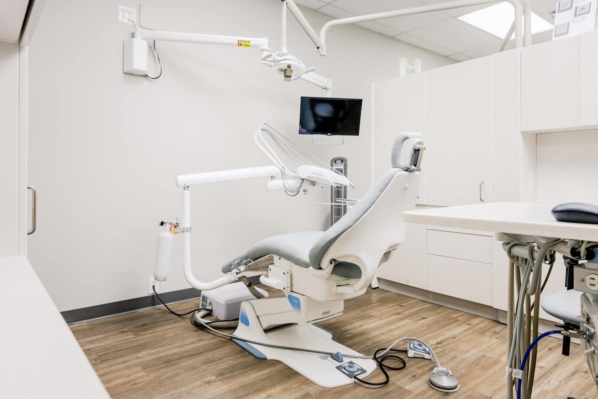 A dental treatment room, with the chair, overhead light and instrument tray ready for the next patient.