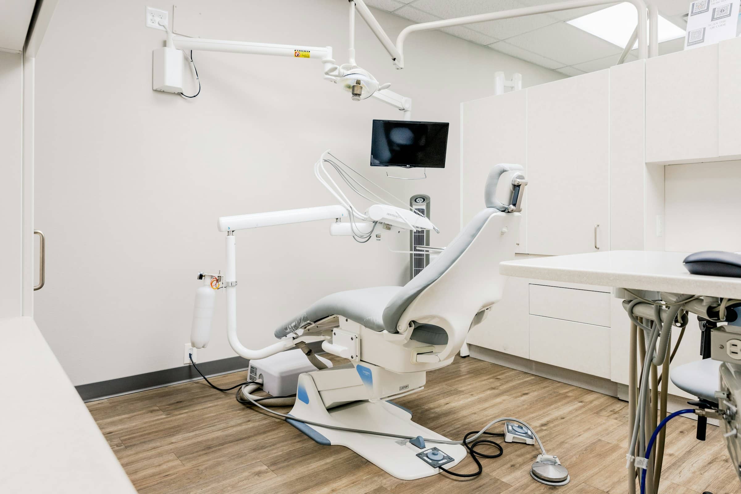 An empty dental treatment room, with the chair, overhead light and instrument tray ready for the next patient.